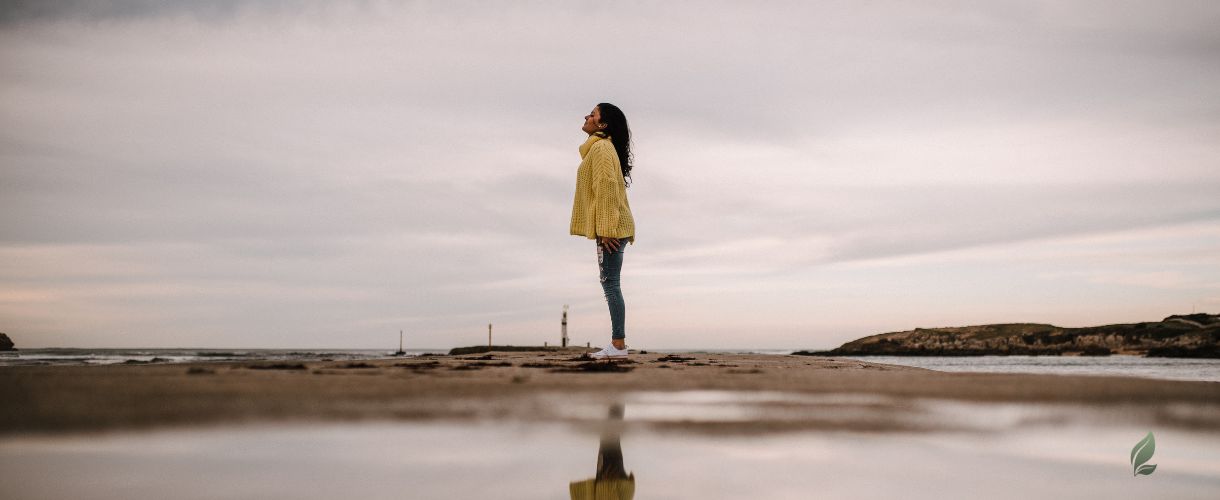 a woman standing and reflecting on life at beach